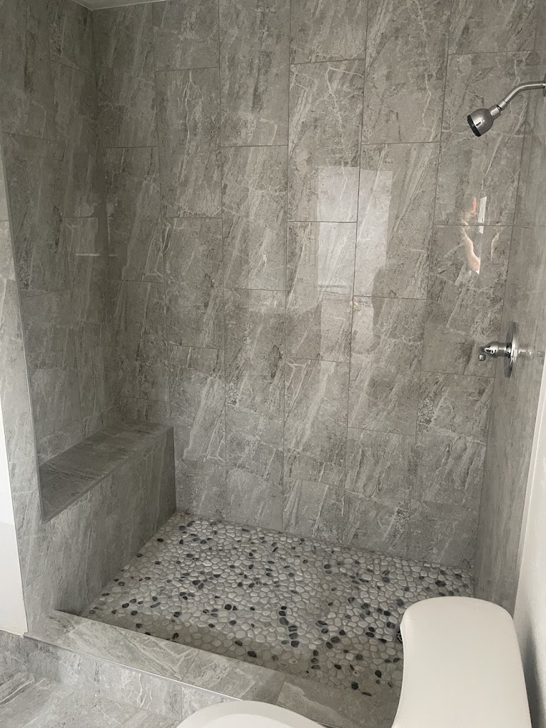 Gray tile shower with built-in bench and pebble floor