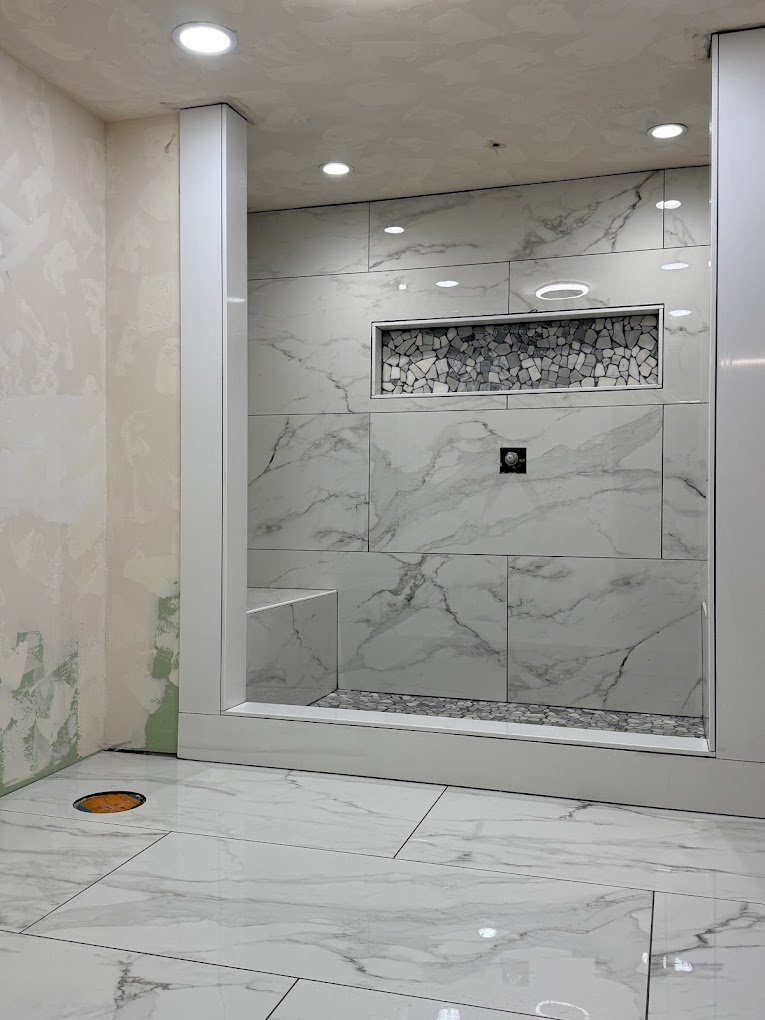 Marble tile shower with mosaic accent niche